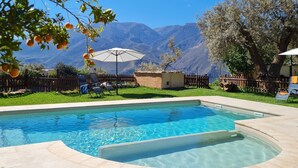 Une piscine avec vue sur les montagnes, une clôture en bois et un petit bâtiment.