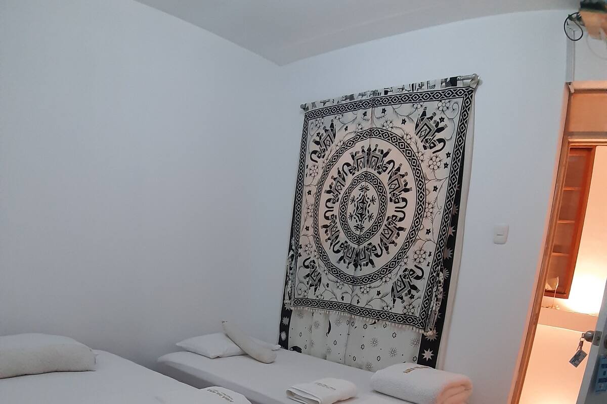 A room with two beds, a tapestry, and a small table.