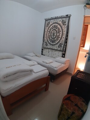 A room with two beds, a tapestry, and a small table. - Casa Aura del Mar (Máncora)