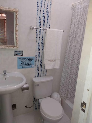 A bathroom with a toilet, sink, and shower curtain. - Casa Aura del Mar (Máncora)
