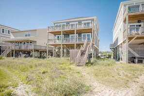 Un hôtel situé en bord de mer, composé de bâtiments à plusieurs étages, doté de balcons en bois et donnant sur une plage de sable.