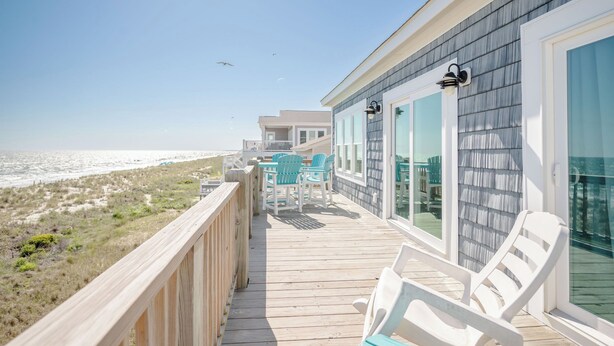 A wooden deck with chairs and a table overlooking the beach. - Salt & Light: Spacious, Custom-built, Oceanfront Home Close to Splash Pad, Park (Oak Island)