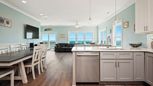 A spacious kitchen with a central island, white cabinetry, and a large window offering a view. - Salt & Light: Spacious, Custom-built, Oceanfront Home Close to Splash Pad, Park (Oak Island)