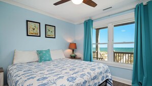 A bedroom with a bed, a nightstand, a lamp, and a window with curtains. - Salt & Light: Spacious, Custom-built, Oceanfront Home Close to Splash Pad, Park (Oak Island)