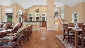 Amplia sala de estar con una mesa de comedor y sillas, cocina con vistas y una escalera que conduce a un nivel superior.