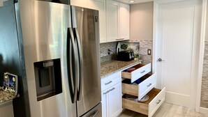 A modern kitchen with stainless steel appliances, white cabinetry, and a granite countertop. - Vacation Home 6 minutes to the beach, heated pool, free canoe, free wifi  (Bonita Springs)