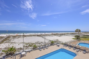 Un resort frente a la playa con piscina, sillas de descanso y vistas al océano.