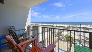 Un balcón con vista a la playa, que incluye una piscina y mobiliario de exterior.