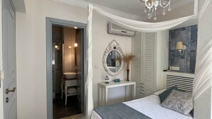 Une chambre à coucher avec un lit, une table de chevet, un miroir et un lustre.