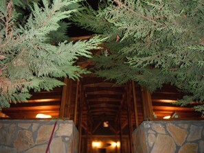 A wooden structure with stone walls and a stone floor, surrounded by evergreen trees. - Kamelya Butik Otel (Bozcaada)