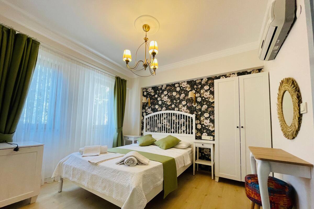 A bedroom with a bed, bedside table, and a small desk with a chair.