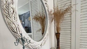 Un meuble-lavabo de salle de bain agrémenté d’un miroir blanc orné, d’un objet décoratif bleu et d’un vase contenant des plantes séchées.