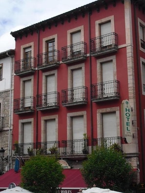 Um edifício vermelho com várias varandas e uma placa que indica que é um hotel.