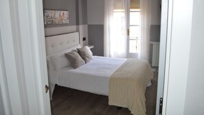 A bedroom with a bed, a nightstand, a wall-mounted artwork, and a window with curtains. - Hotel Los Robles (Cangas de Onis)