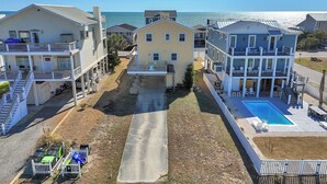 A residential area with multiple houses, a swimming pool, and a view of the ocean. - Sandtrap: Oceanview House on West Beach with Easy Beach Access. (Oak Island)