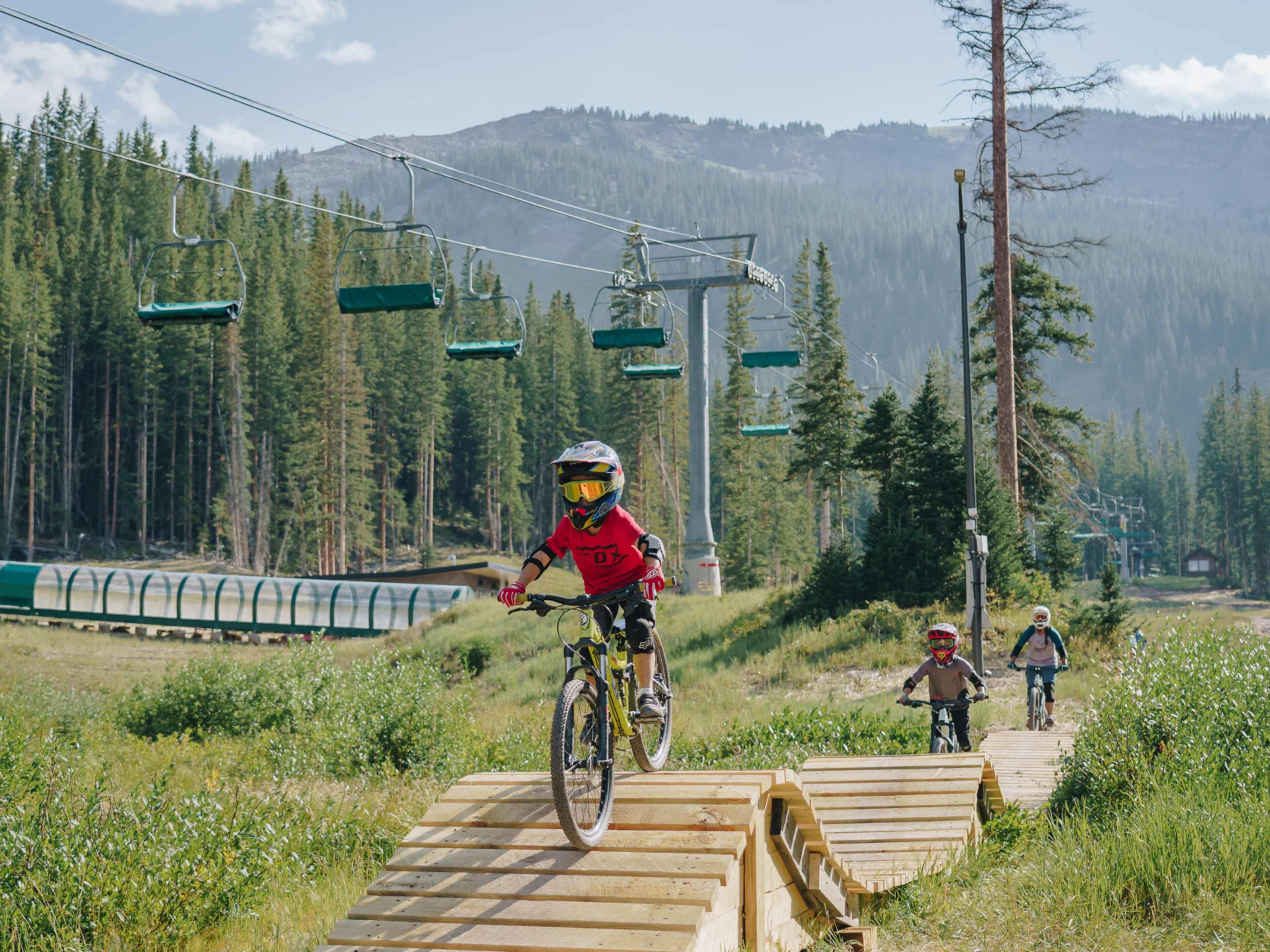 Ein Mountainbike-Weg mit Holzrampen und einer Seilbahn im Hintergrund.