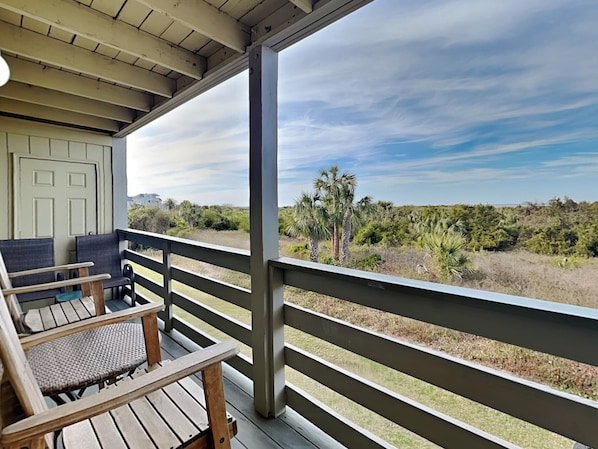 A covered outdoor area with wooden furniture and a view of a natural landscape.