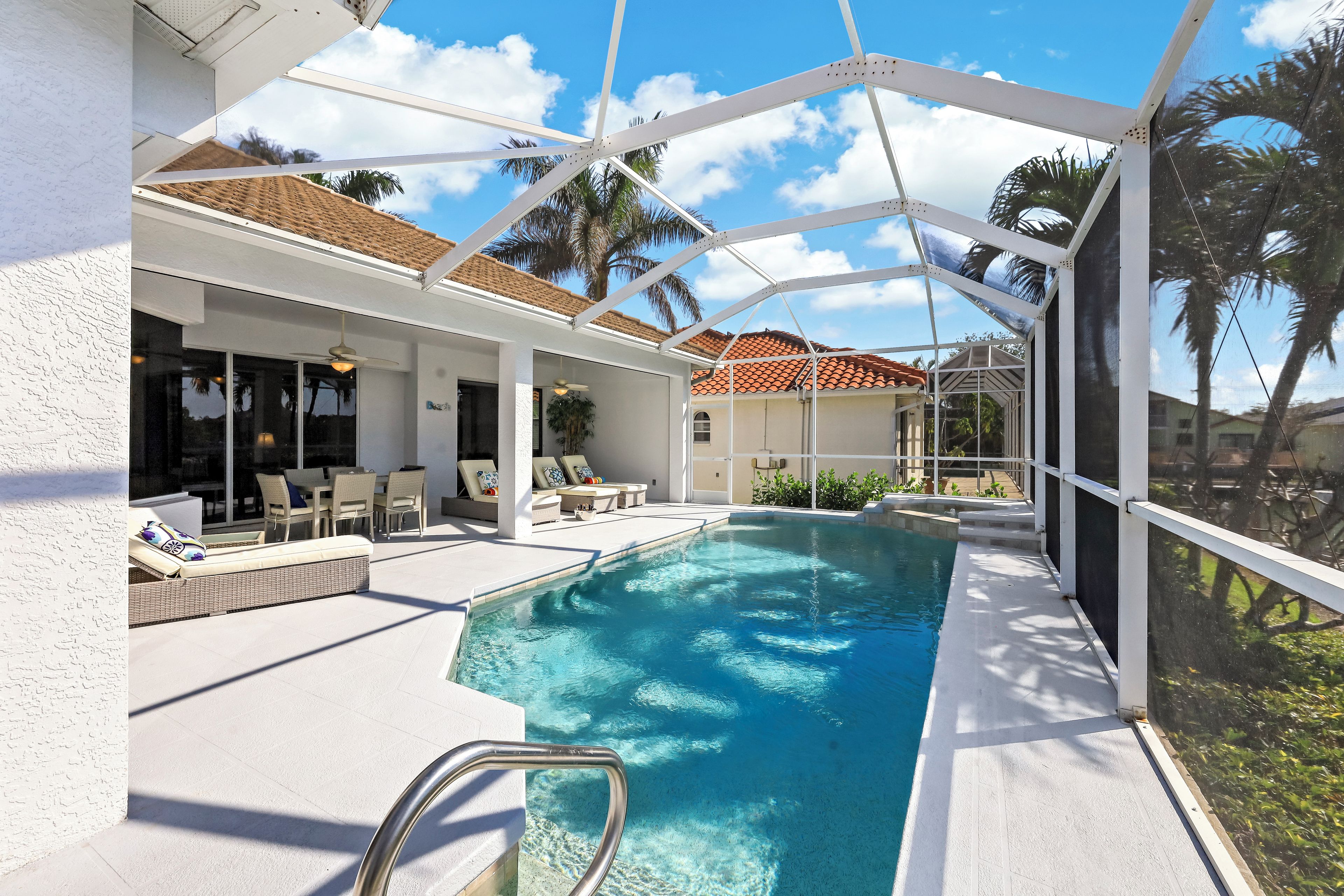 A covered outdoor swimming pool with lounge chairs and a patio area.