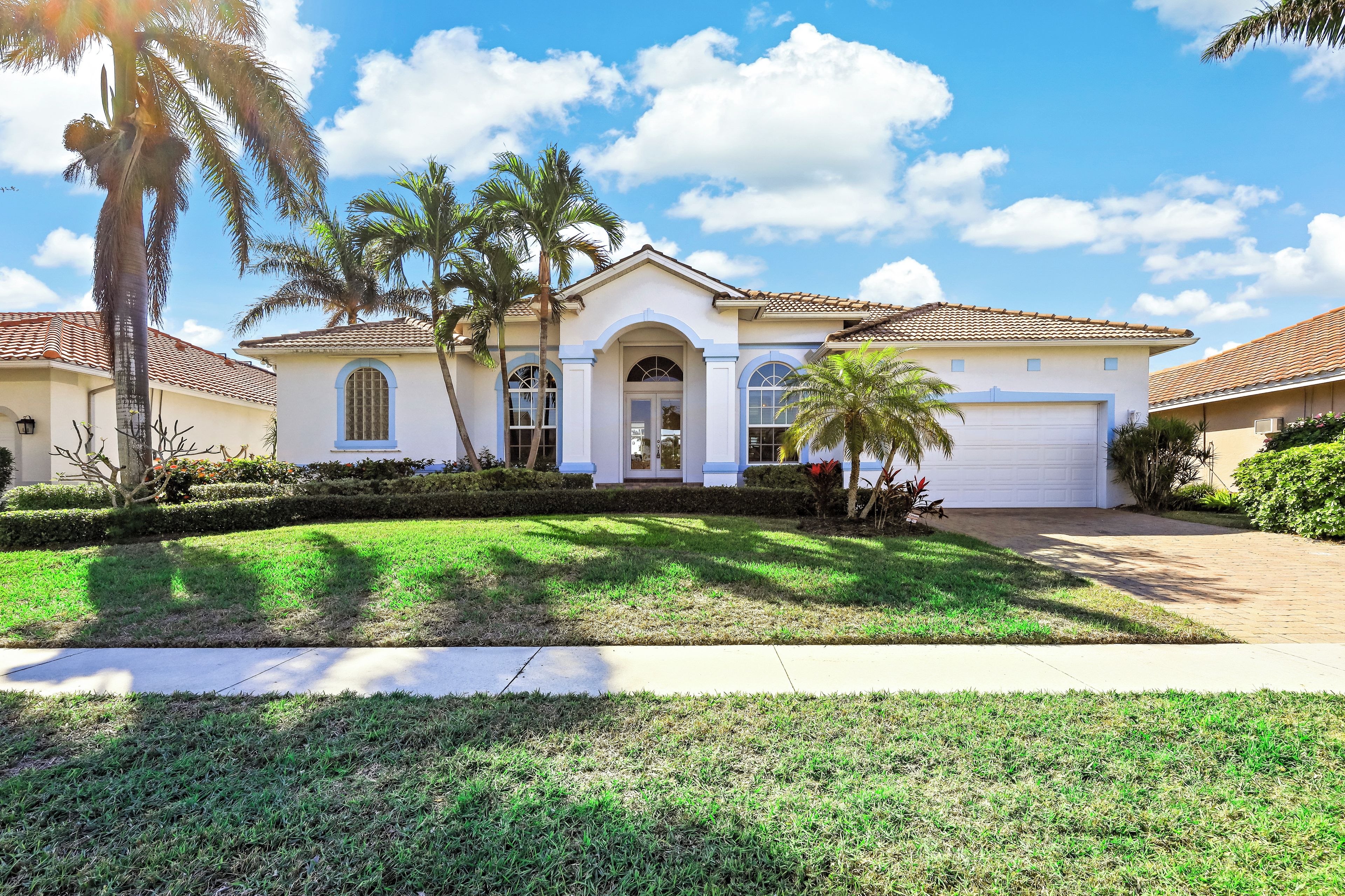 A two-story house with a white facade, a central arched entrance, and a garage.