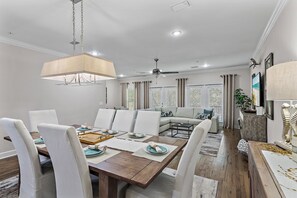 Un comedor con una mesa de madera, sillas blancas y una lámpara colgante.