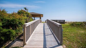 Une promenade en bois mène à une zone d’observation abritée, d’où l’on a une vue dégagée sur la plage et les dunes.