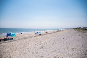 En strand med parasoller och folk.