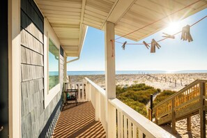 A wooden deck with a view of the beach and ocean.