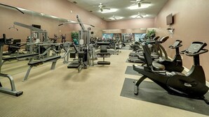 A gym with various exercise equipment, ceiling fans, and a large mirror. - Large Updated BEAUTIFUL 2BR, 2 BATH Condo! Walk to Beach, Pool & More! (Corpus Christi)