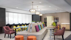 Un espace de détente moderne comprenant un canapé, des poufs orange et différents types de fauteuils.