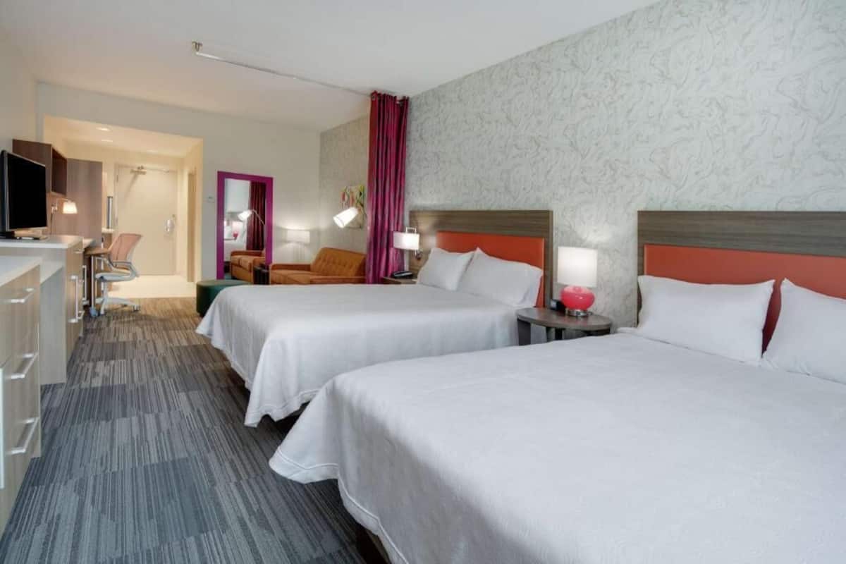 Une chambre d’hôtel avec deux lits, un bureau, une chaise, une télévision et une salle de bain.