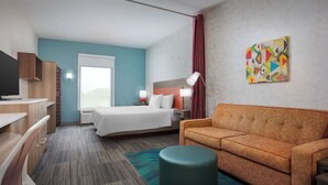 Une chambre d’hôtel avec un lit, un canapé, un bureau et une télévision.