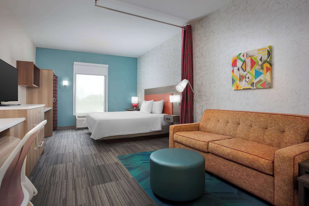 Une chambre d’hôtel avec un lit, un canapé, un bureau et une télévision.