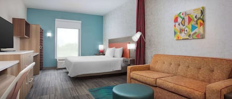 Una habitación de hotel con cama, sofá, escritorio y televisor.