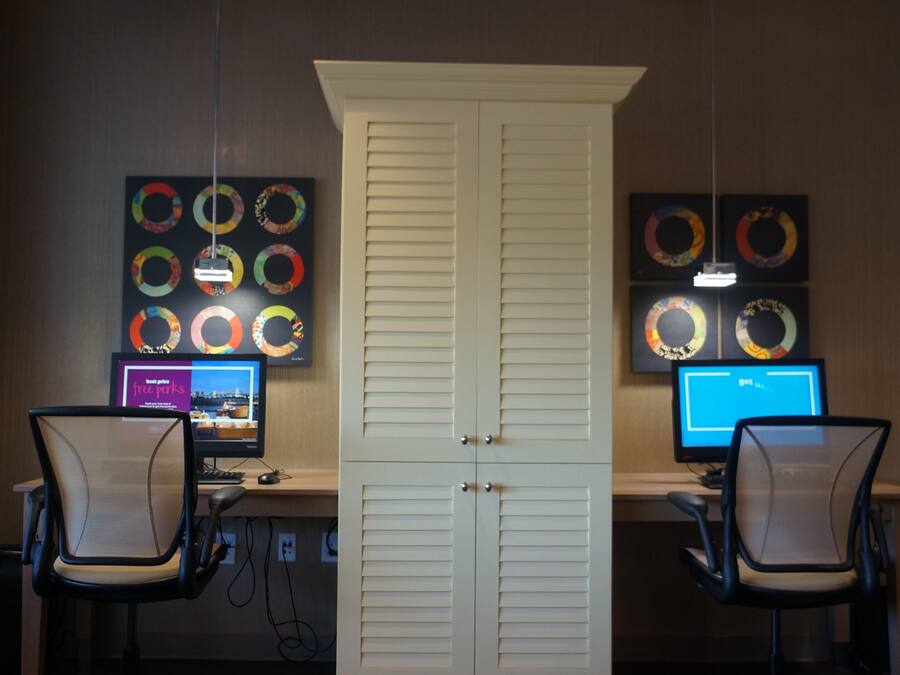 A room with two desks, each with a computer monitor, chairs, and a white door.