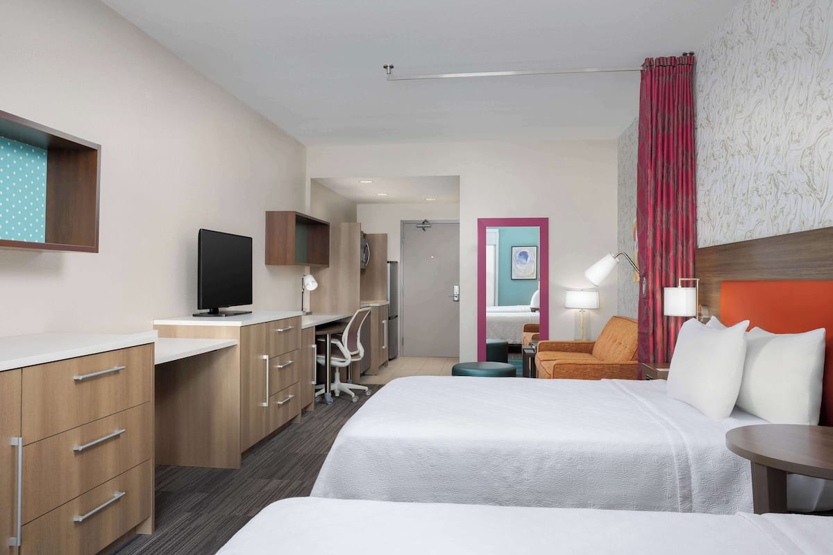 Une chambre d’hôtel avec un lit, un bureau équipé d’un ordinateur, une télévision et une salle de bain visible à travers une porte ouverte.