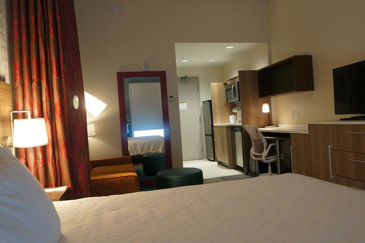 Une chambre d’hôtel équipée d’un lit, d’un bureau, d’une chaise, d’une télévision et d’une kitchenette.