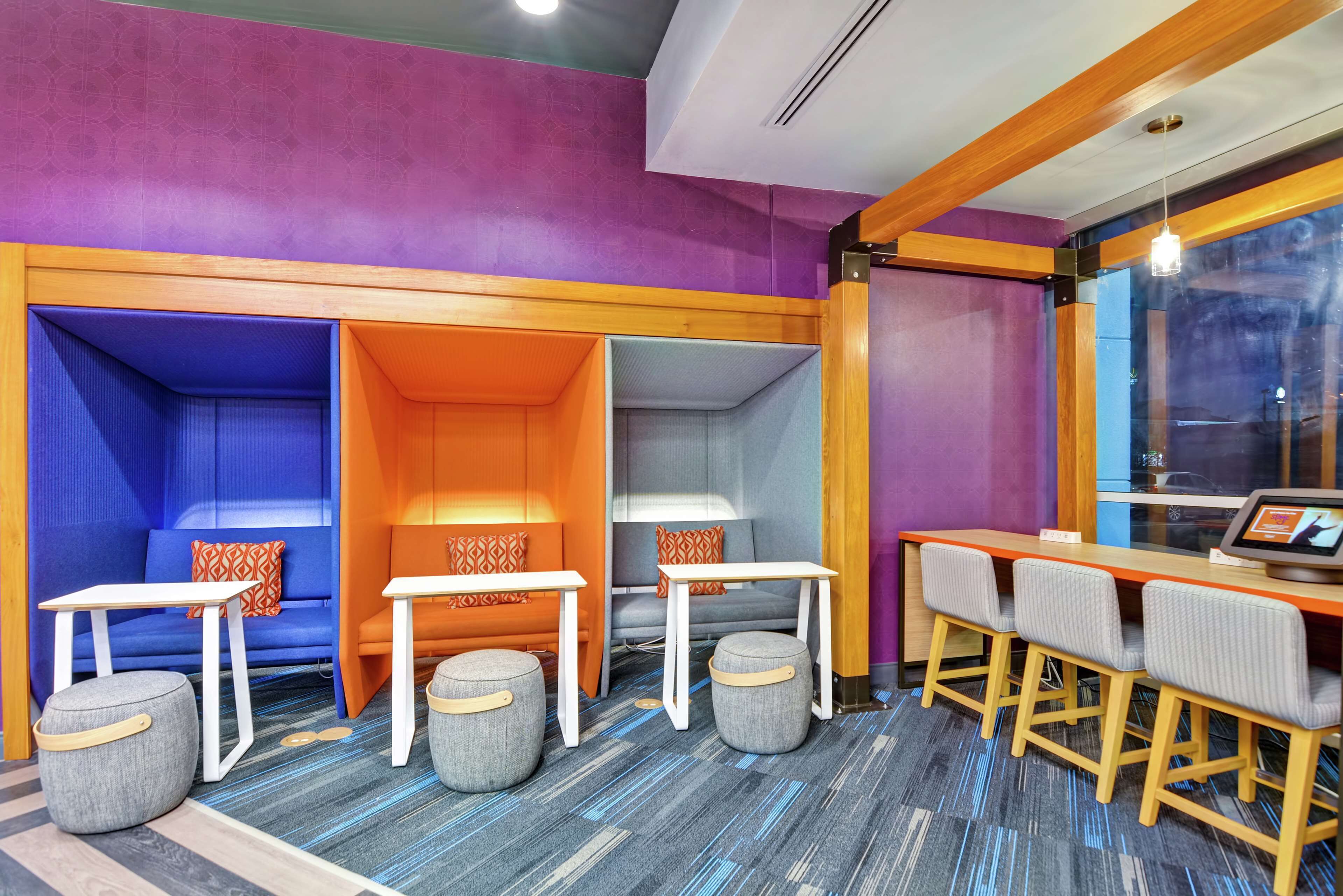 A vibrant room with a purple and orange color scheme, featuring a sofa, ottomans, a table, and bar seating.