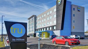 A modern hotel building with a blue and grey facade, a prominent 'tru by Hilton' sign, and several parked cars in the foreground. - Tru by Hilton Richmond (Richmond)