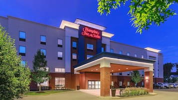 A Hampton Inn & Suites hotel with a covered entrance, multiple windows, and a parking area.