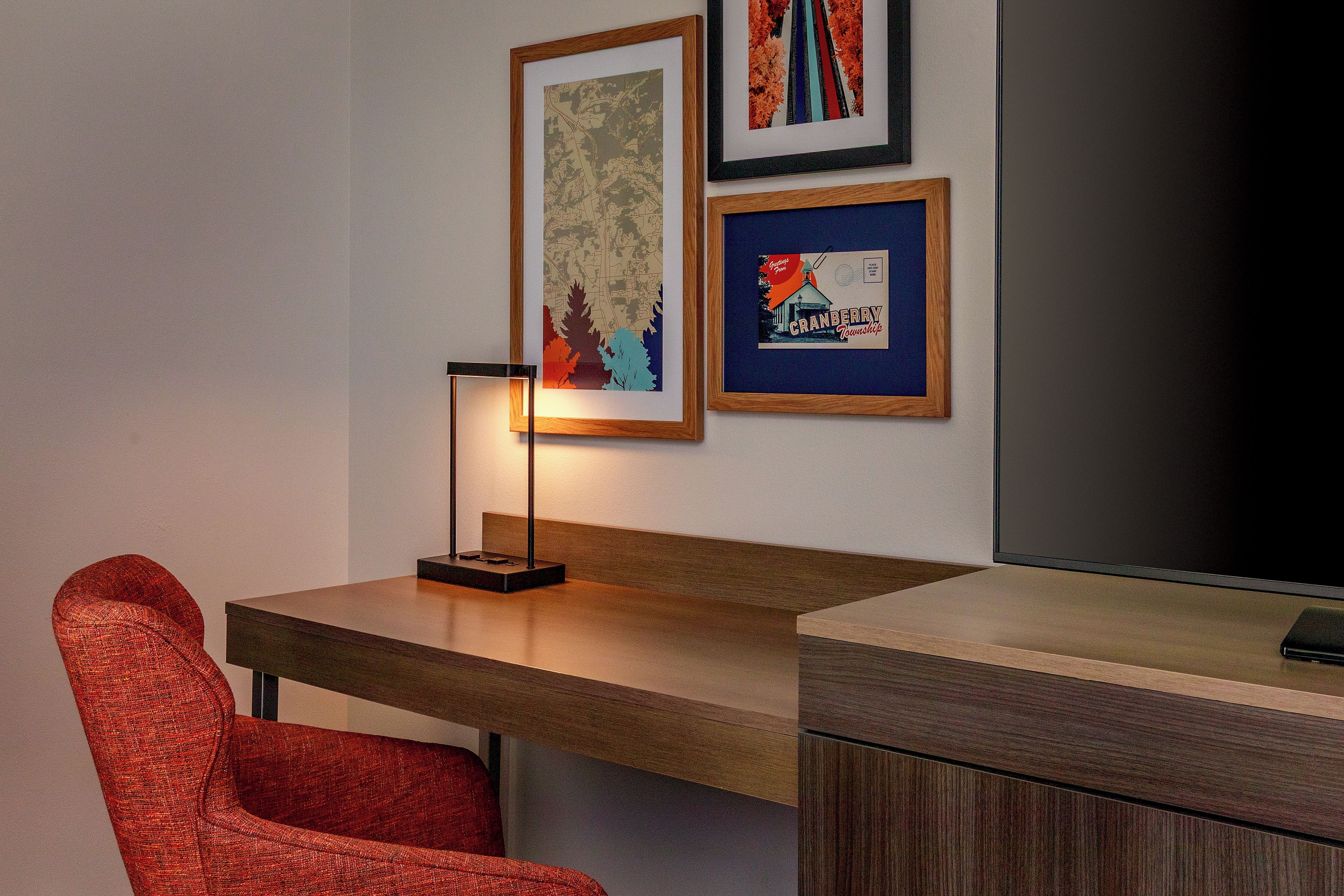 Una habitación con un escritorio, una silla y un mapa enmarcado en la pared.