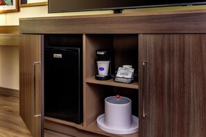 Una kitchenette equipada con cafetera, refrigerador y basurero.
