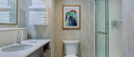 A modern bathroom with a glass shower enclosure, a toilet, and a sink with a marble countertop.