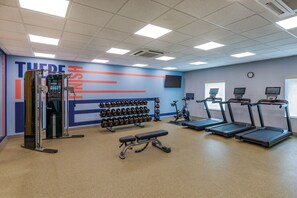 A gym with exercise equipment, treadmills, and dumbbells.