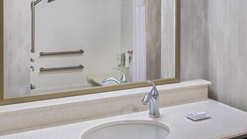 A bathroom with a sink, mirror, and shower.