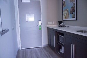 A modern kitchen with dark cabinets, a white countertop, and a stainless steel sink. - Hampton Inn & Suites Cranberry Pittsburgh (Cranberry Township)