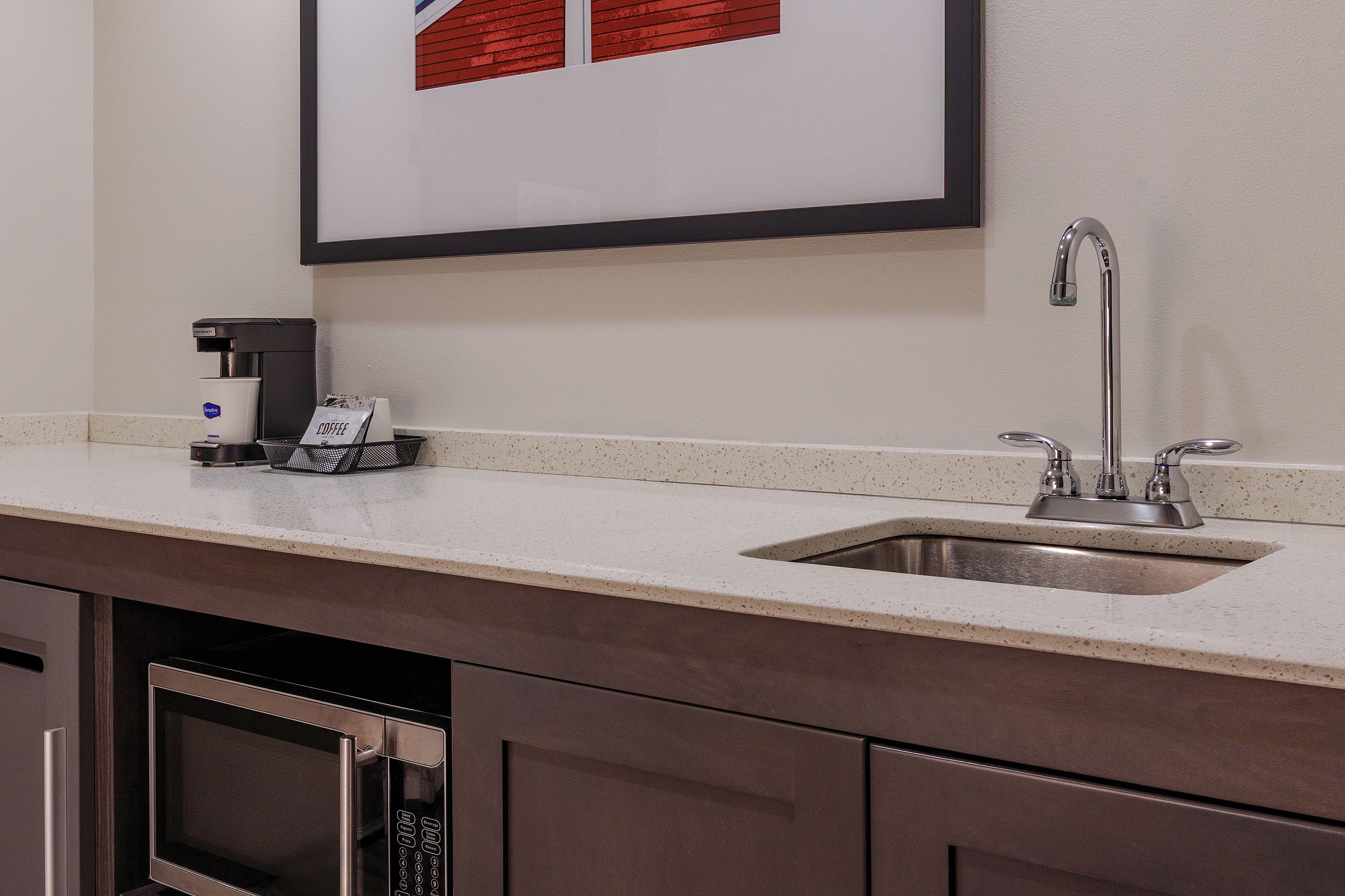 A kitchen with a built-in coffee maker, a stainless steel sink, and a dishwasher.