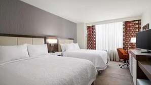 A hotel room with two beds, a desk with a chair, a television, and a window with curtains. - Hampton Inn & Suites Guymon (Guymon)