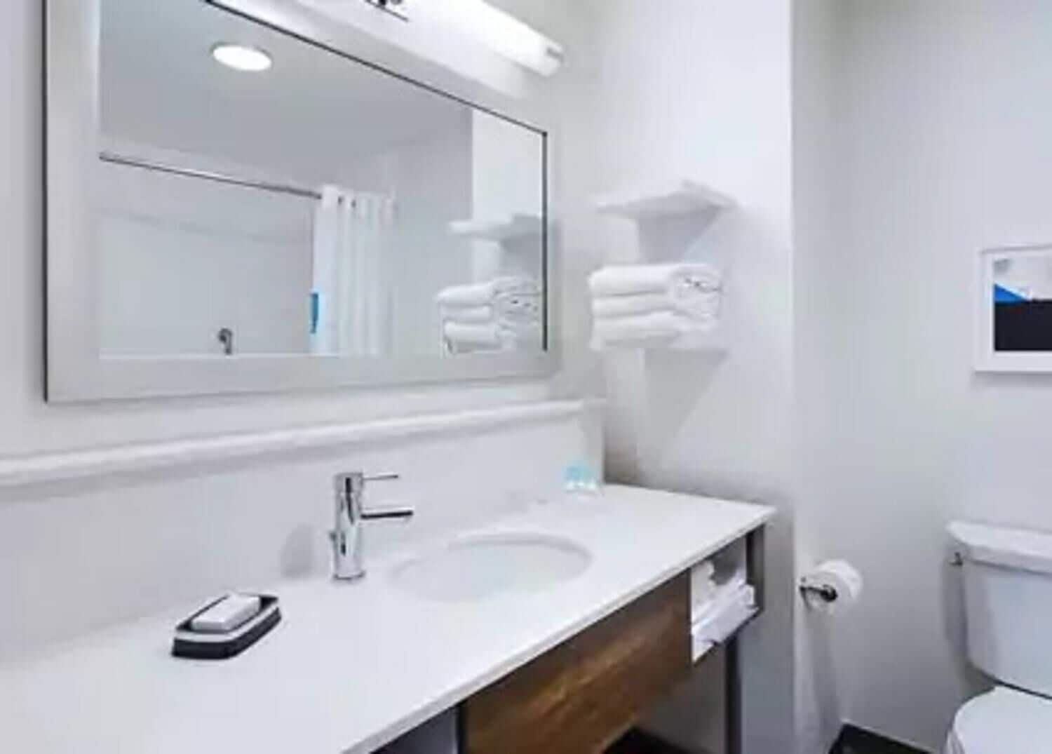 A bathroom with a white sink, a mirror, a towel rack, and a toilet.