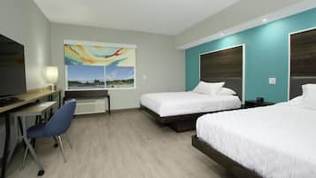 A hotel room with two beds, a desk with a chair, a TV, and a painting of a landscape.