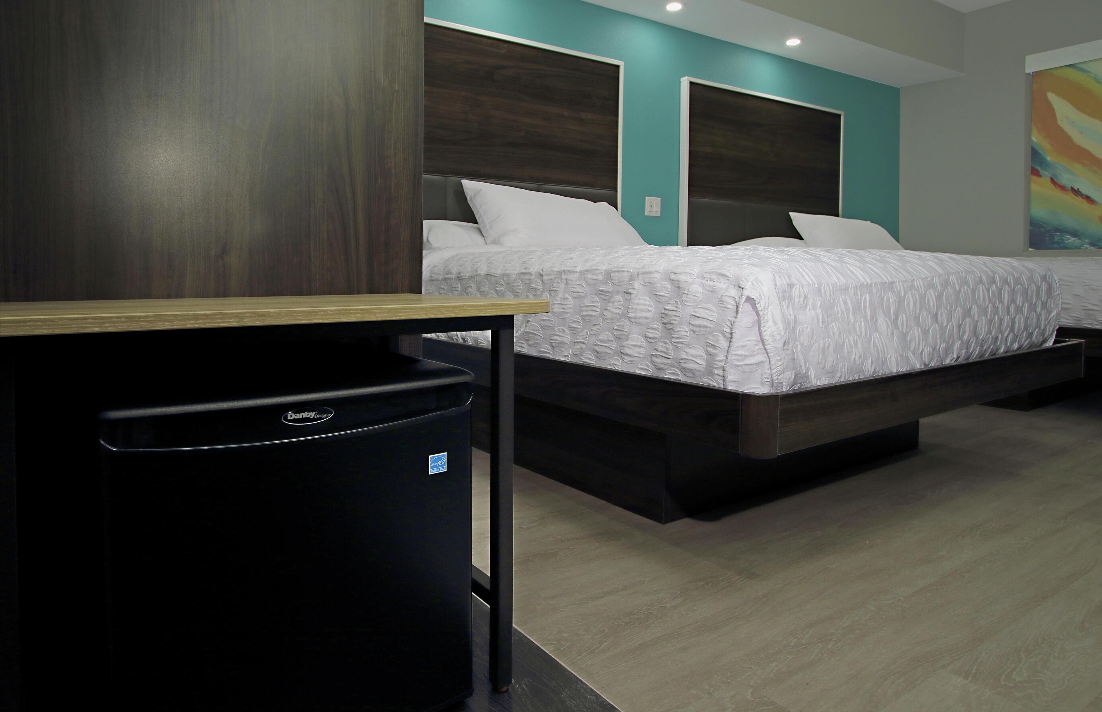 A modern hotel room with a bed, a desk, and a trash bin.